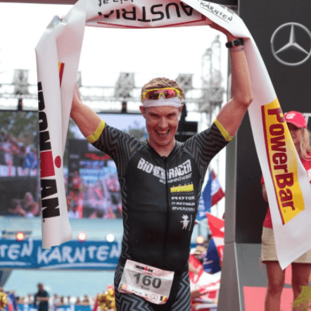 Ironman Sam Gyde winning race holding ribbon